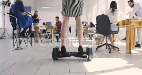 相机折叠腿年轻自信的老板商务妇女骑电动滑板车在现代时尚阁楼办公室视频的预览图