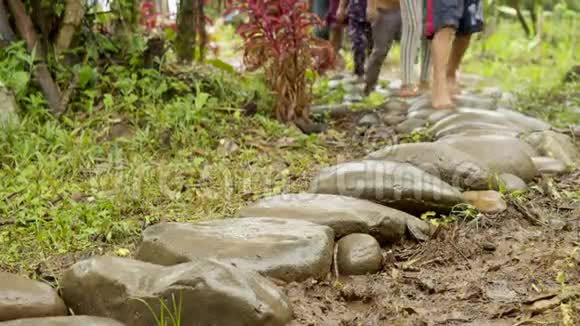 赤脚的腿在热带雨林的某个地方的岩石上行走视频的预览图