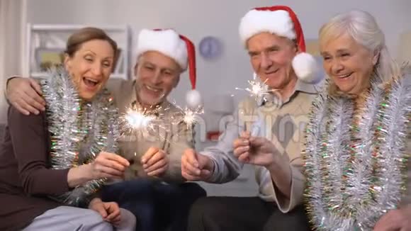 戴着圣诞老人帽子的男人和拿着星星之火的金盆洗手的女人新年视频的预览图
