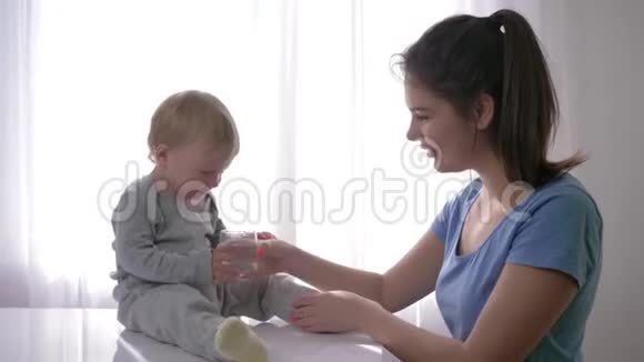 解渴的小孩哭闹的男婴从母亲手中的杯子里喝纯净水解渴视频的预览图