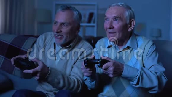 情绪化的老年男性朋友拿着操纵杆玩电子游戏很有趣视频的预览图