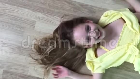 无忧无虑的少女趴在木地板上微笑着对着镜头在木制摄像机前摆姿势的快乐女孩模特视频的预览图