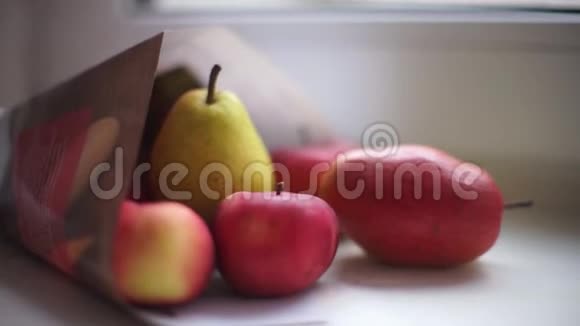 成熟的红苹果和梨子放在窗台上的纸袋里特写侧景视频的预览图