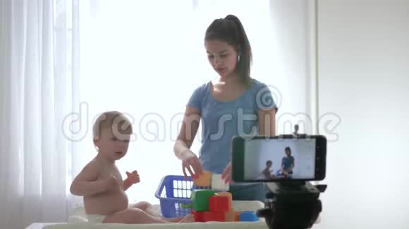 视频直播可爱的小男孩和妈妈一起玩教育玩具并为vlog拍摄新的一集视频的预览图