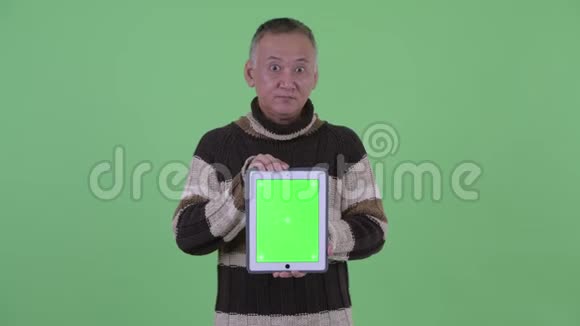 快乐成熟的日本男人展示数码平板电脑看上去很惊讶视频的预览图