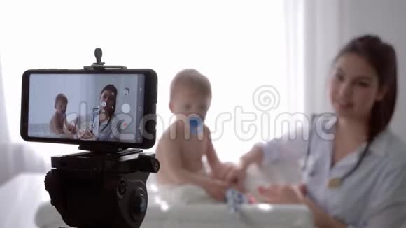 小儿科医生用听诊器专业检查小男孩在录制现场教程视频的预览图