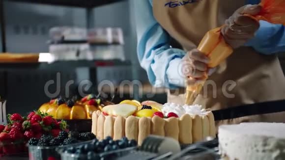 糖果师把奶油放在桌上的水果蛋糕上视频的预览图