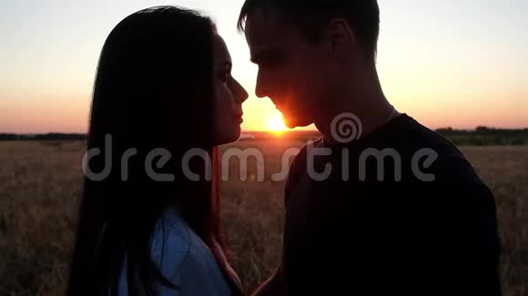 一对相爱的夫妇在夏日日落的背景下接吻视频的预览图