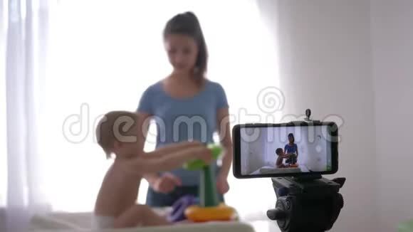 博客教养孩子年轻的母亲博主带着孩子玩玩具同时录制现场教程视频视频的预览图