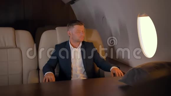 企业家坐在舒适的商务飞机扶手椅上的肖像视频的预览图