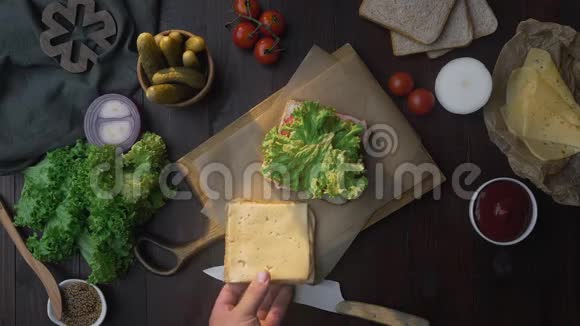 三明治与火腿和沙拉平躺在木板上在光线下厨师的手完成三明治视频的预览图