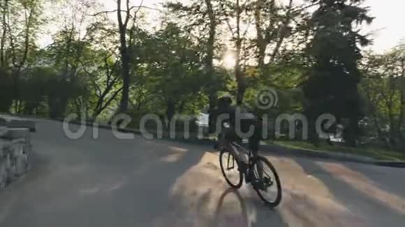 瘦小的运动骑自行车的人在公园里骑公路自行车骑着黑色自行车的骑自行车者穿着黑色的衣服自行车的概念SS视频的预览图