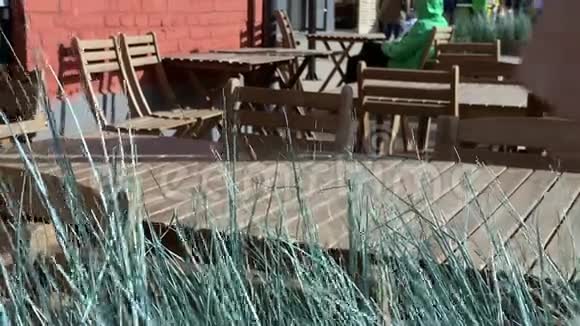 街上的咖啡馆空着木桌背景上模糊的人风中的草动着视频的预览图