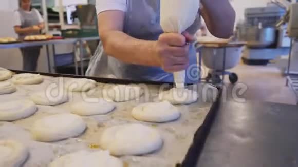 面包师在生产车间添加奶油填充剂视频的预览图