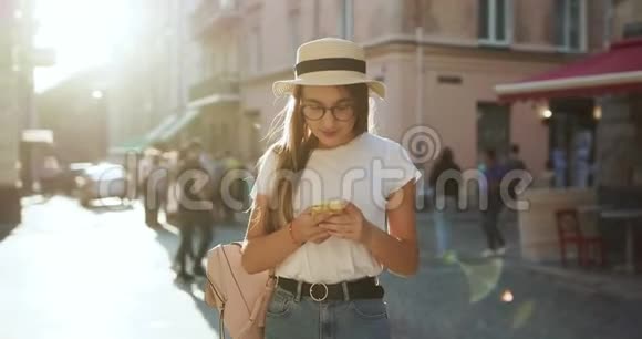 女孩走在街上用手机发短信有魅力的年轻女性在时尚的外观使用应用程序上视频的预览图