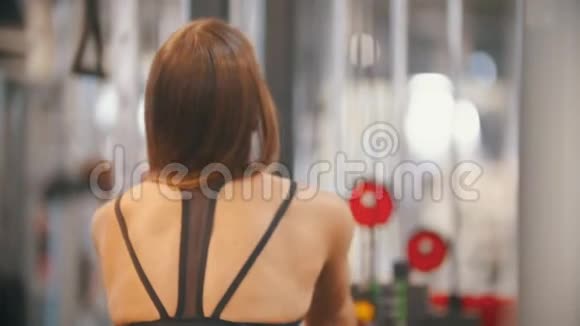 一位在健身房训练的女运动员把手柄拉到重量块上抽胸部肌肉和手视频的预览图