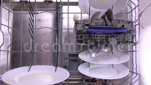男人手把一个白色的脏盘子放进洗碗机的篮子里然后把它推到里面视频的预览图