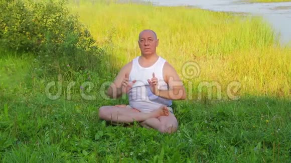 一位中年男子早上在湖上做呼吸瑜伽和冥想视频的预览图