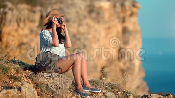 美丽的旅行女性在山顶放松日落时用相机拍摄海景视频的预览图