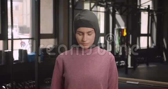 年轻迷人的穆斯林运动女性在健身房交叉双臂看镜头的特写镜头视频的预览图