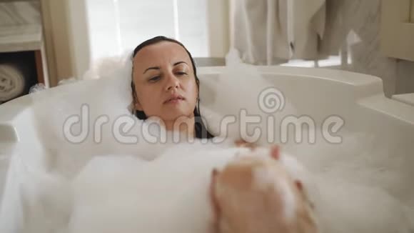 快乐的女人享受充满泡沫的浴缸美丽的女人在家享受水疗视频的预览图