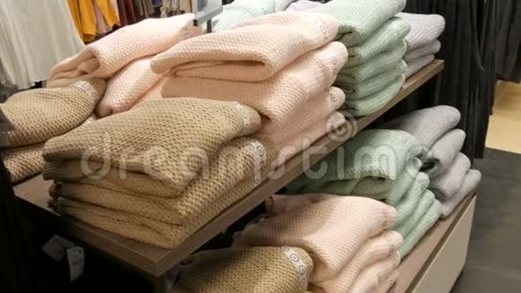在服装店的货架上一排叠在一起的浅色的漂亮温暖的女士针织毛衣视频的预览图