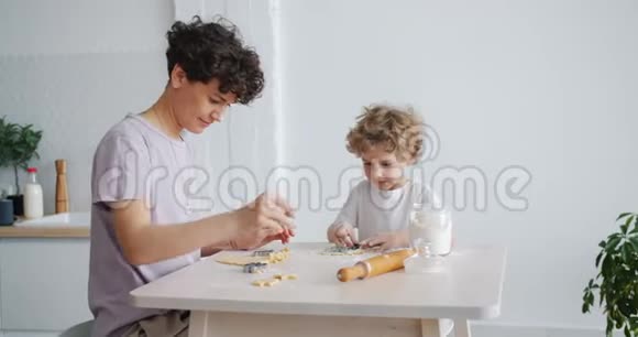 年轻的家庭母亲和孩子在餐桌上做饼干用面团视频的预览图