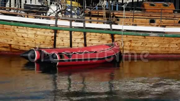 休闲充气红色橡皮艇筏绑在木制游艇的栏杆上的概念场景视频的预览图