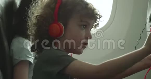 一个小男孩试图调整他的座椅靠背在一架飞机上视频的预览图