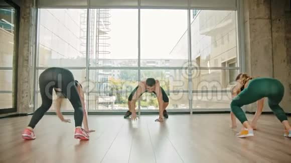 在工作室进行健身训练两名运动妇女和她们的教练靠在地上向前爬行视频的预览图