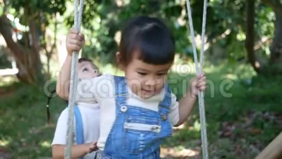 可爱快乐的小女孩喜欢和姐姐在后院玩竹秋千视频的预览图