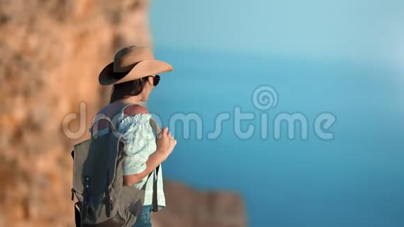 活泼漂亮的徒步旅行者女人背着背包走在山顶上欣赏风景视频的预览图