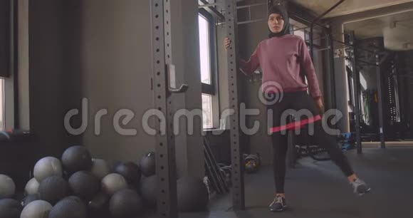 年轻漂亮的穆斯林女性戴头巾在室内健身房做抵抗训练的特写照片视频的预览图