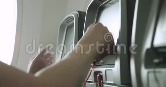 母亲在飞机上帮助孩子使用座椅靠背触摸屏设备视频的预览图
