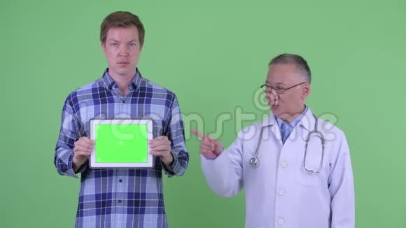 快乐成熟的日本男医生年轻男子展示数码平板电脑竖起大拇指视频的预览图