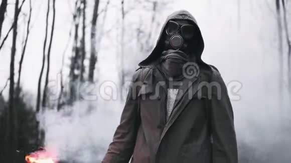 戴着防毒面具的人站在空寂的森林里手里拿着红色的信号火视频的预览图