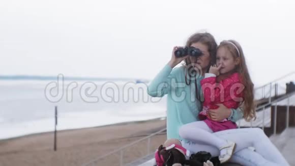 一个女人带着女儿在海滩上看望远镜视频的预览图