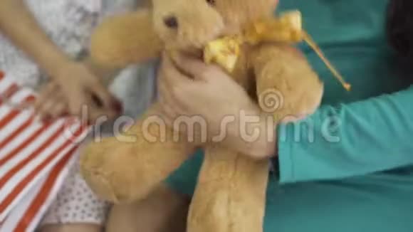柔软的黄色泰迪熊用丝弓特写女性手拿着礼物穿丝绸蓝绿色衣服的孕妇视频的预览图