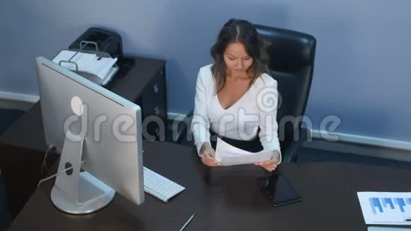 漂亮的商务小姐在办公室里用数码平板电脑和文件视频的预览图