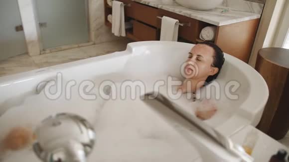沐浴的女人在充满泡沫的浴中放松视频的预览图