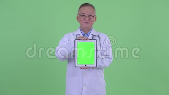 快乐成熟的日本男子医生思考显示数字平板电脑视频的预览图