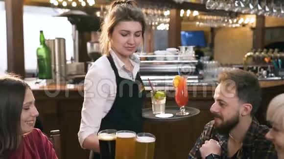 专注的年轻女服务员为年轻学生朋友提供啤酒和鸡尾酒视频的预览图