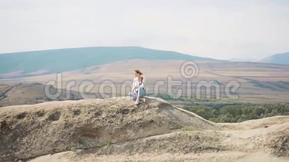 迷人的年轻女子金发碧眼一个人穿着宽松的衣服坐在佐治亚州的山顶上清晨沉思视频的预览图