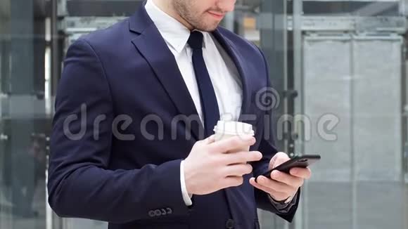 年轻自信的商人喝外卖咖啡使用智能手机视频的预览图