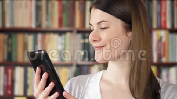 女大学生在大学图书馆使用电子书背景书架视频的预览图