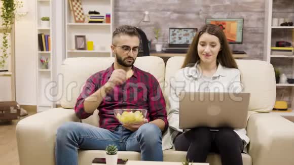 快乐的年轻夫妇坐在沙发上网购视频的预览图