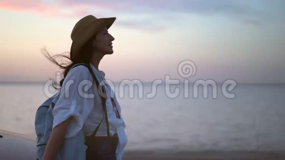 迷人的旅行女性在日落时在海滩上放松享受令人惊叹的海景中景视频的预览图