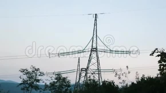 喀尔巴阡山上的电塔在绿色森林中在日落时顶着灰色的天空绿树之间的电力塔视频的预览图