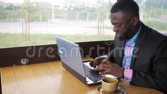 美国黑人商人正在笔记本电脑上输入一条信息喝一杯咖啡视频的预览图