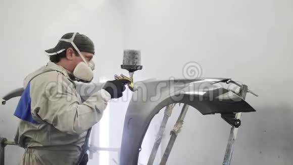 男性专家在喷漆室内对车身金属细节进行染色视频的预览图